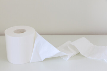 Unrolled soft white tissue roll (toilet roll, loo roll, bog roll) on white table, hygiene concept