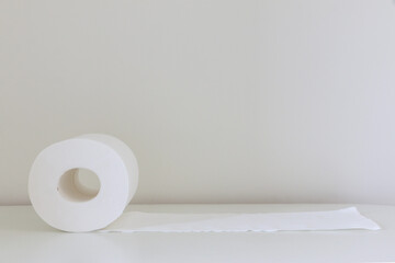 Soft white tissue roll (toilet roll, loo roll, bog roll) unrolled on white table, hygiene concept, copy space above