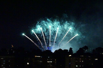 Fireworks illuminate night sky over silhouetted cityscape in Madrid, Spain