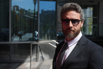 Mature business man standing outdoor on modern office building. Business success. Business man thinking outdoor. Modern businessman in full suit standing outdoors near office cityscape.