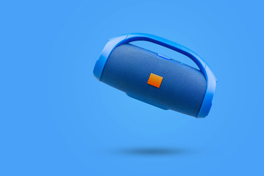 Blue portable wireless Bluetooth speaker, on a blue background. Device for playing music.