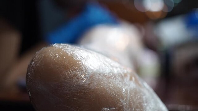 Blurred young female apprentice make a tattoo on rubber synthetic leg at tattoo studio 