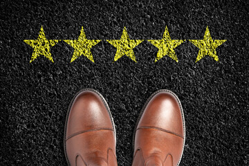 Men's boots on the asphalt road. Five yellow stars. View from above. Evaluation concept. Business. Lifestyle.