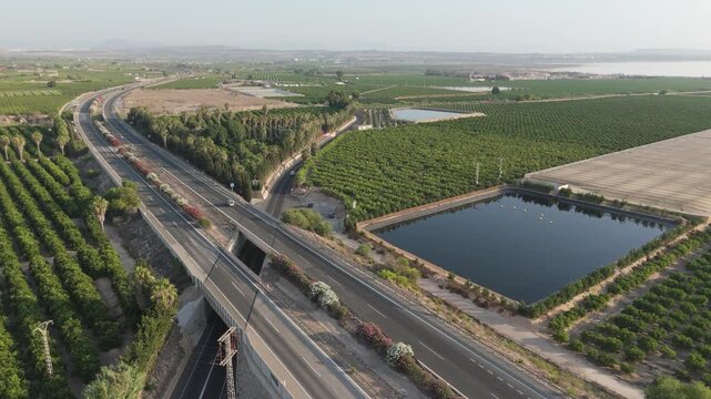 Elevated view from a drone highlights a blend of rural charm and busy highway life near the AP7, with nearby camping and citrus groves.

