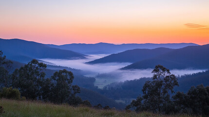 Obraz premium Breathtaking Sunrise Over Mountain Range with Pink and Orange Sky, Mist Gently Covering Valleys Below, Capturing the Serenity of Nature