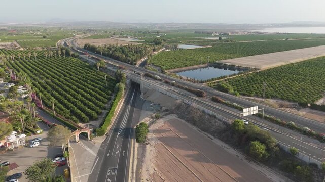 Elevated view from a drone highlights a blend of rural charm and busy highway life near the AP7, with nearby camping and citrus groves.
