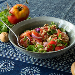 bowl of georgian salad with tomatoes and walnuts on the table