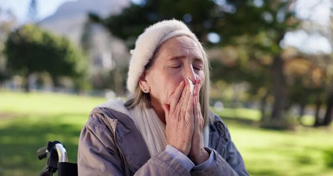 Senior woman, sick and sneezing with tissue in park for pollen allergies, flu virus and health risk. Elderly person, toilet paper and blowing nose in nature for sinus problem, hayfever and bacteria