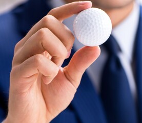 Young businessman with golf ball working in office
