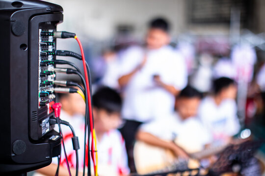 Close-up of multiple cables and wires plugged into the back of an audio amplifier mixer during a live music concert.