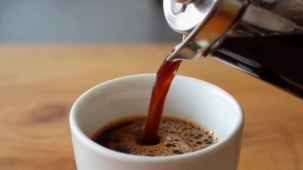 A close up of coffee being poured into a cup, evoking warmth and comfort in a relaxing café setting