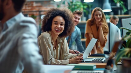 Group of young professionals in office setting collaborate on project. Businessmen and businesswomen sit around table, laptops open, engaged in discussion.