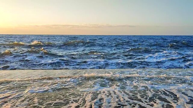 Storm at dawn sunset. Storm at sea. Large high sea waves with white foam hitting concrete pier wall and splashing on sunny summer day. Stormy sea. Rough sea. Shore. Nature. Natural background