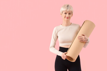 Sporty young woman with fitness mat on pink background