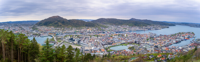 Stunning panorama of Bergen, Norway, showing the charming city harbor, colorful houses and surrounding mountains. The iconic Bryggen district can be seen in the foreground.
