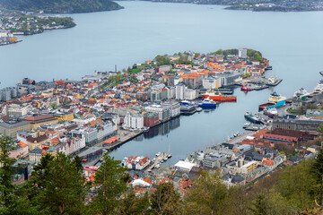 Stunning panorama of Bergen, Norway, showing the charming city harbor, colorful houses and surrounding mountains. The iconic Bryggen district can be seen in the foreground.