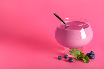 Glass of fresh blueberry smoothie with mint and berries on pink background
