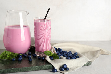 Glass and jug of fresh blueberry smoothie with mint on white background