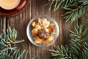 Frankincense resin in a bowl with spruce tree branches and candle