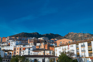 Scenic view of a Mediterranean town with white and terracotta buildings against mountain backdrop