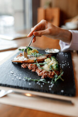 delicious dish with juicy chicken, fresh green vegetables, and buckwheat with a sour cream and creamy sauce on a beautiful black plate in a cozy and nice restaurant