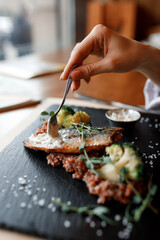 delicious dish with juicy chicken, fresh green vegetables, and buckwheat with a sour cream and creamy sauce on a beautiful black plate in a cozy and nice restaurant