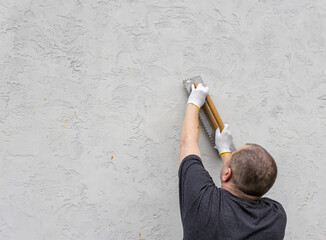 A craftsman meticulously creates a textured finish on a newly prepared wall, showcasing skill and...
