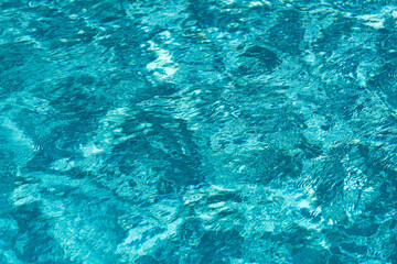 Blue pool water background. Blurred transparent clear calm water surface texture. Water waves in sunlight with copy space.