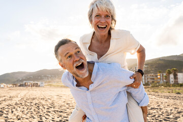 Beautiful happy senior couple dating at the seaside during summertime - Mature married couple in love bonding outdoors at the beach, concepts about elderly lifestyle, relationship and quality of life