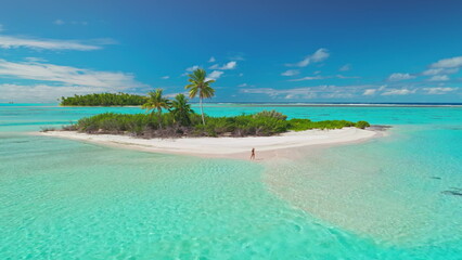 A woman walks along a pristine white sand beach, surrounded by lush palm trees and crystal clear turquoise water in the Maldives.
