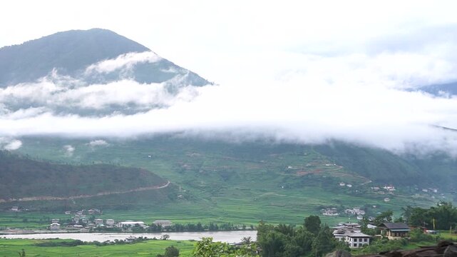 Time-lapse View Punakha rice terraces in punakha landscape with mountain hill fog clouds look at Bhutanese traditional village and river flowing through. Destination place that everyone must travel