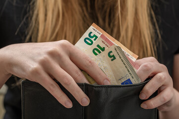 Kobieta wkładająca pieniądze do portfela, banknoty euro