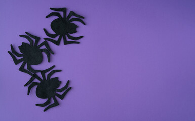 Three black felt spiders on a purple background. Copy space