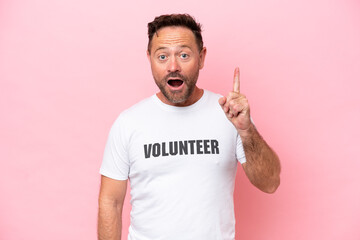 Middle age volunteer man isolated on pink background isolated on pink background thinking an idea pointing the finger up