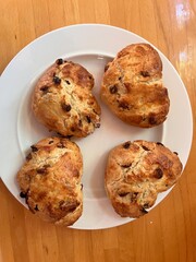 Scones shaped and cut in the shape of romantic heart fruit currant home made mix the four scones on grease proof paper baking tray for cooking flat lat view close up for valentine on white plate wood