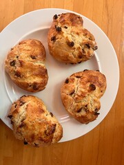 Scones shaped and cut in the shape of romantic heart fruit currant home made mix the four scones on grease proof paper baking tray for cooking flat lat view close up for valentine on white plate wood