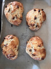 Scones shaped and cut in the shape of romantic heart fruit currant home made mix the four scones on grease proof paper baking tray for cooking flat lat view close up for valentine on white plate wood