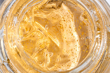 24k gold skin care cream gel in a glass jar close up. Beauty treatment product texture macro