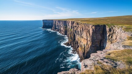 Obraz premium Amazing coastal landscape with steep cliffs overlooking the deep blue ocean, waves crashing against the rocks under a clear bright sky