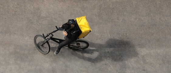  delivery company rider waiting for customer, client and looking at screen of mobile phone. top...