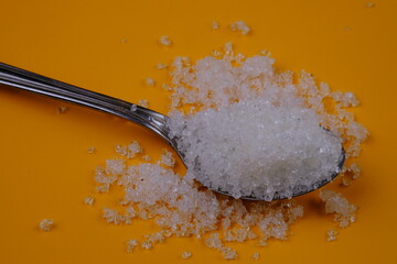granulated sugar in a spoon. natural sweetener made from sugar cane juice. spoonful of sugar.
