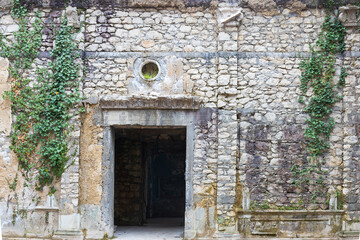 Empty doorway in the stone wall of a building. The stone wall of the house is covered with green ivy. Background with copy space