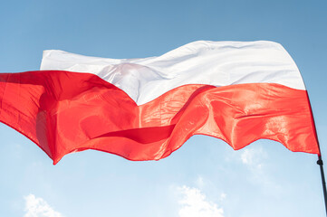 Powiewająca flaga biało czerwona. Flaga Polski na tle niebieskiego nieba © smoku7979