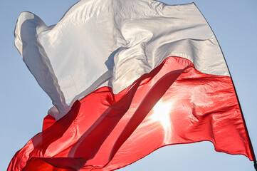 Powiewająca flaga biało czerwona. Flaga Polski na tle niebieskiego nieba © smoku7979