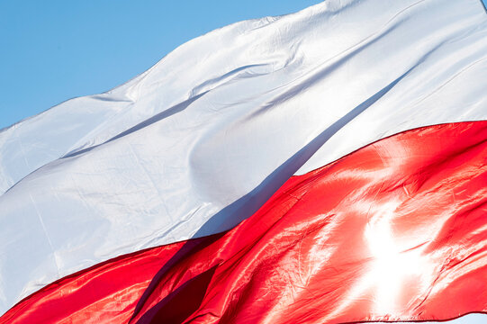 Powiewająca flaga biało czerwona. Flaga Polski na tle niebieskiego nieba