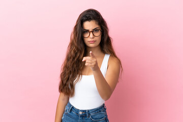 Young caucasian woman isolated on pink background frustrated and pointing to the front