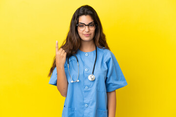 Young surgeon doctor woman isolated on yellow background pointing with the index finger a great idea