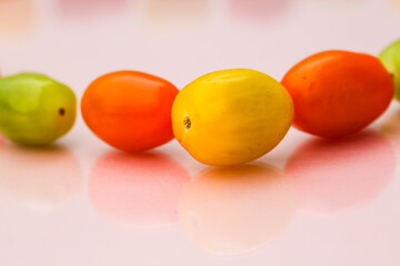 Cocktail tomatoes in different colors, red, orange, green, yellow on pastel background