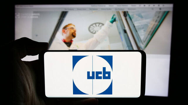 Stuttgart, Germany - 07-25-2024: Person holding cellphone with logo of Belgian biopharmaceutical company UCB S.A. in front of business webpage. Focus on phone display.