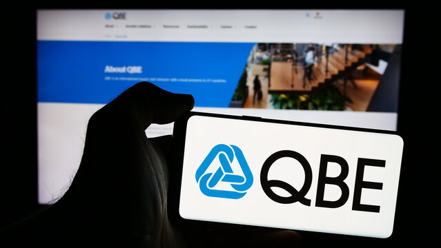 Stuttgart, Germany - 07-25-2024: Person holding smartphone with logo of Australian company QBE Insurance Group Limited in front of website. Focus on phone display.